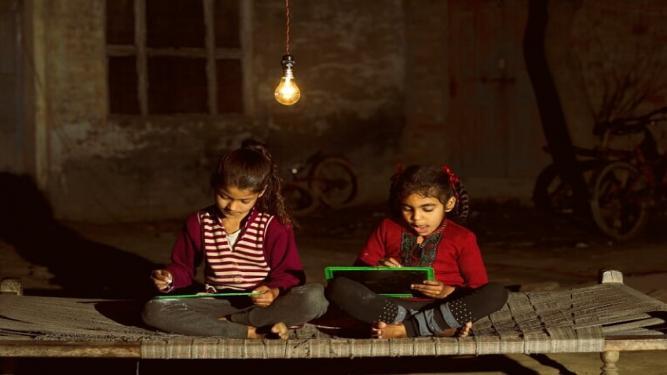 Kids writing on a slate, using a light bulb